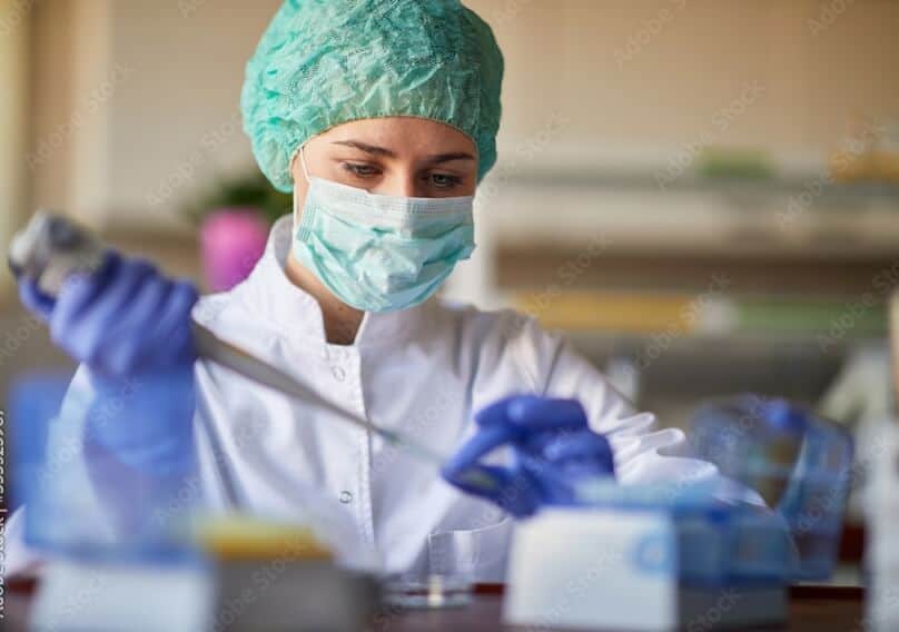 A scientist uses a dropper to add a substance to a vial