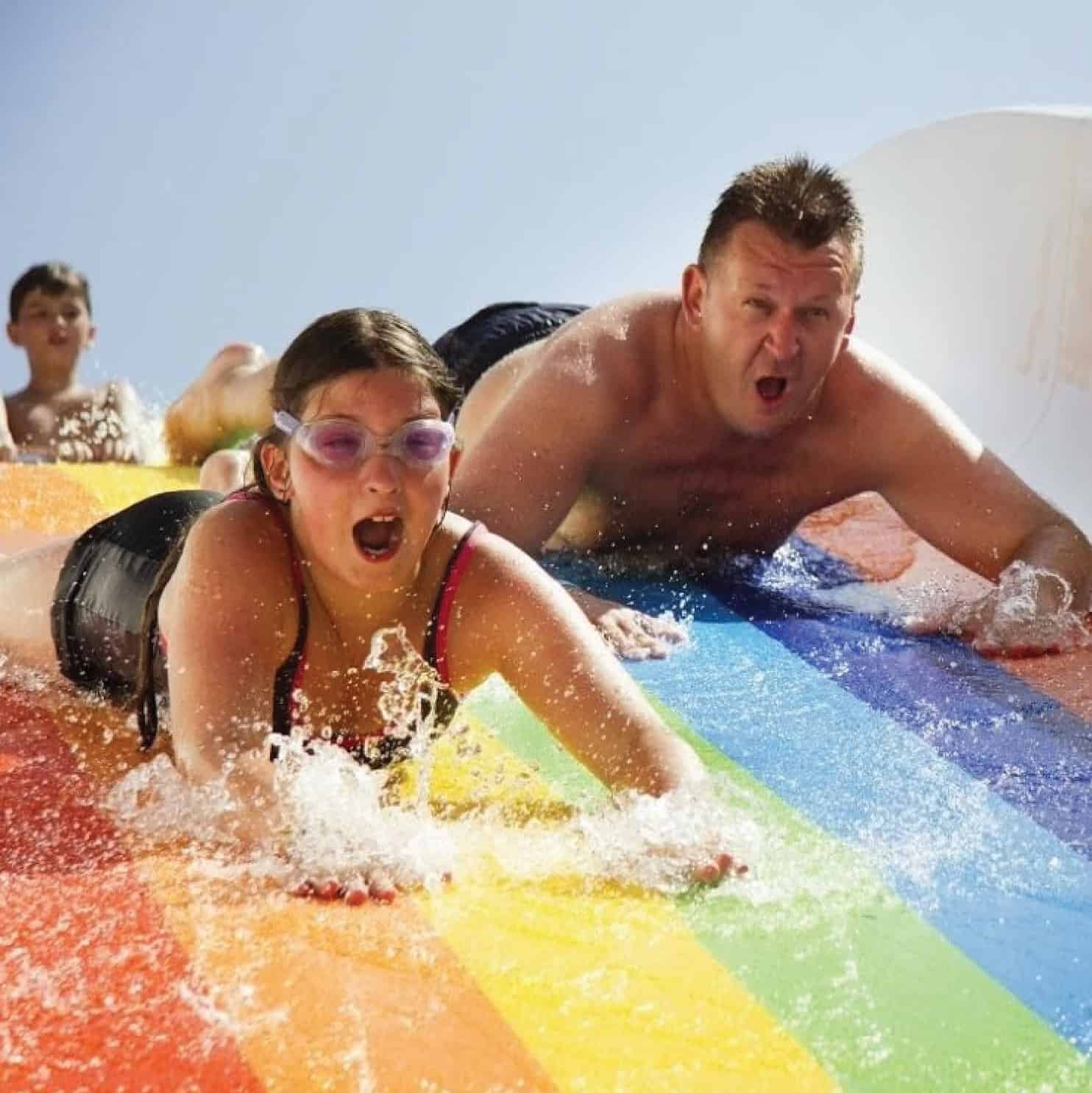 People sliding on a rainbox slip and slide